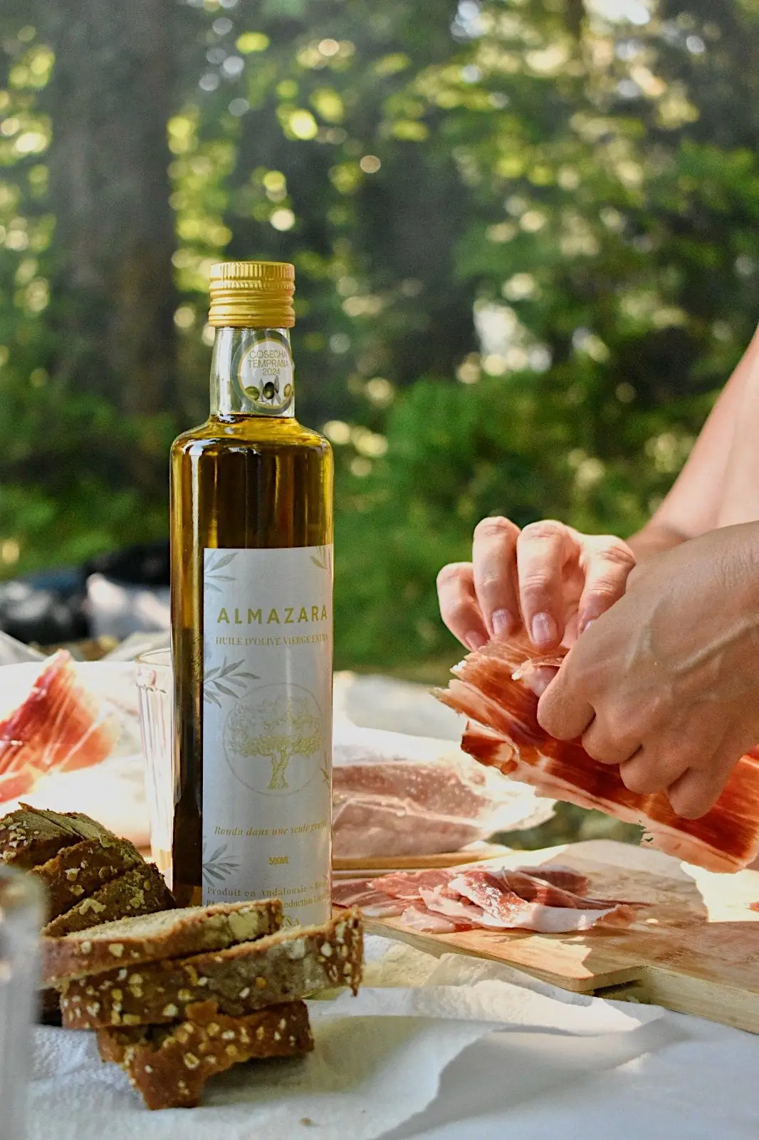 Aceite de oliva ALMAZARA, pan y jamón en la mesa
